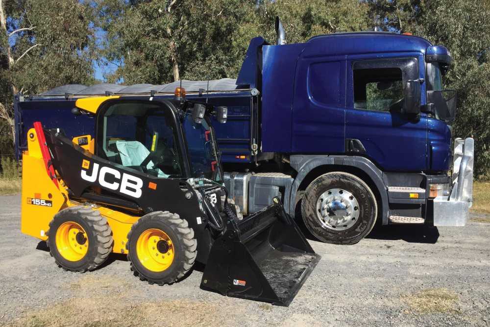 A blue tipper truck next to a bobcat, ready for bulk delivery of quarry or landscaping products in Murrumbateman and the Yass Valley